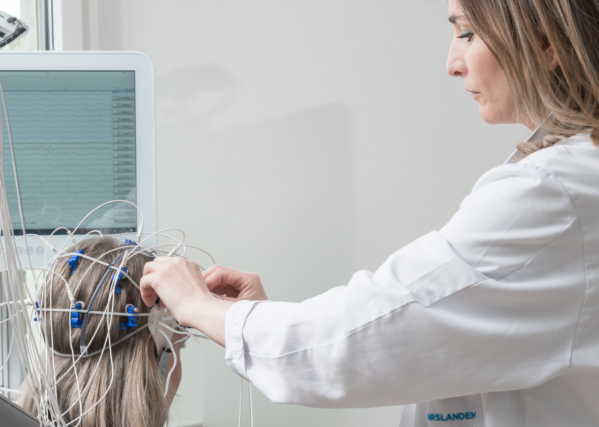 Eine Mitarbeiterin des Neurozentrums St. Gallen befestigt EEG-Elektroden am Kopf einer Patientin.