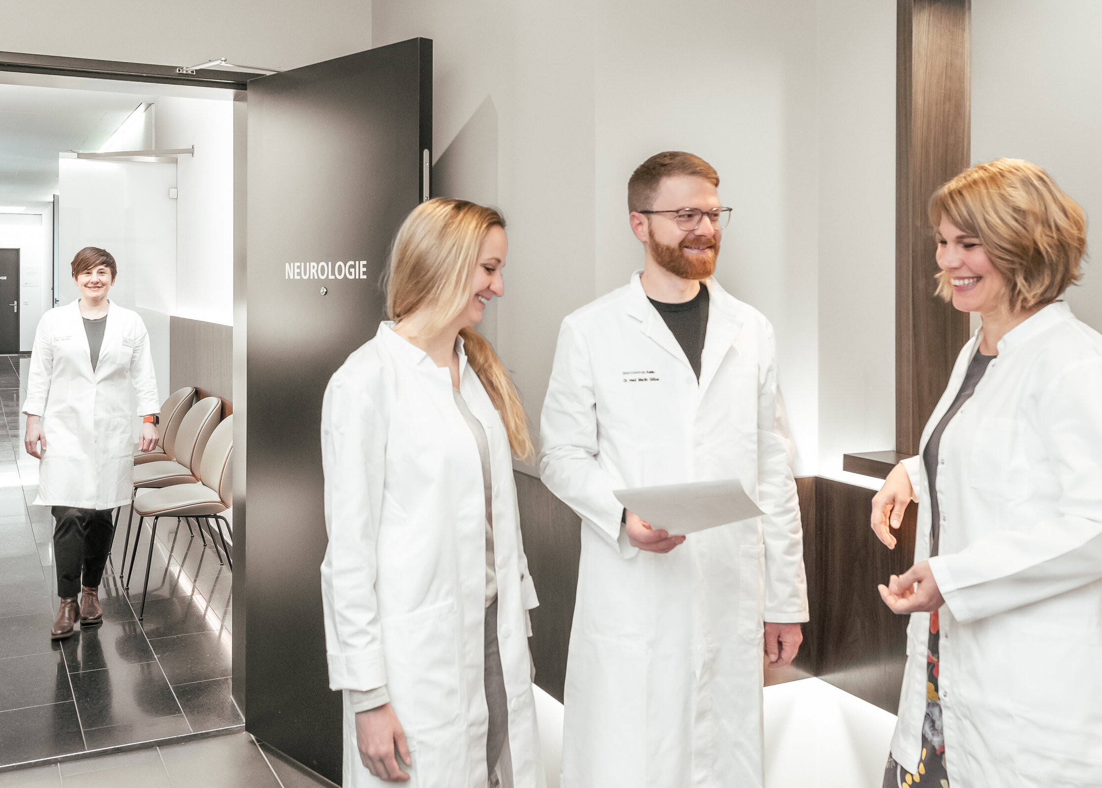 Drei Neurologen stehen im Gang des Neurozentrums Aarau und besprechen ein Dokument.