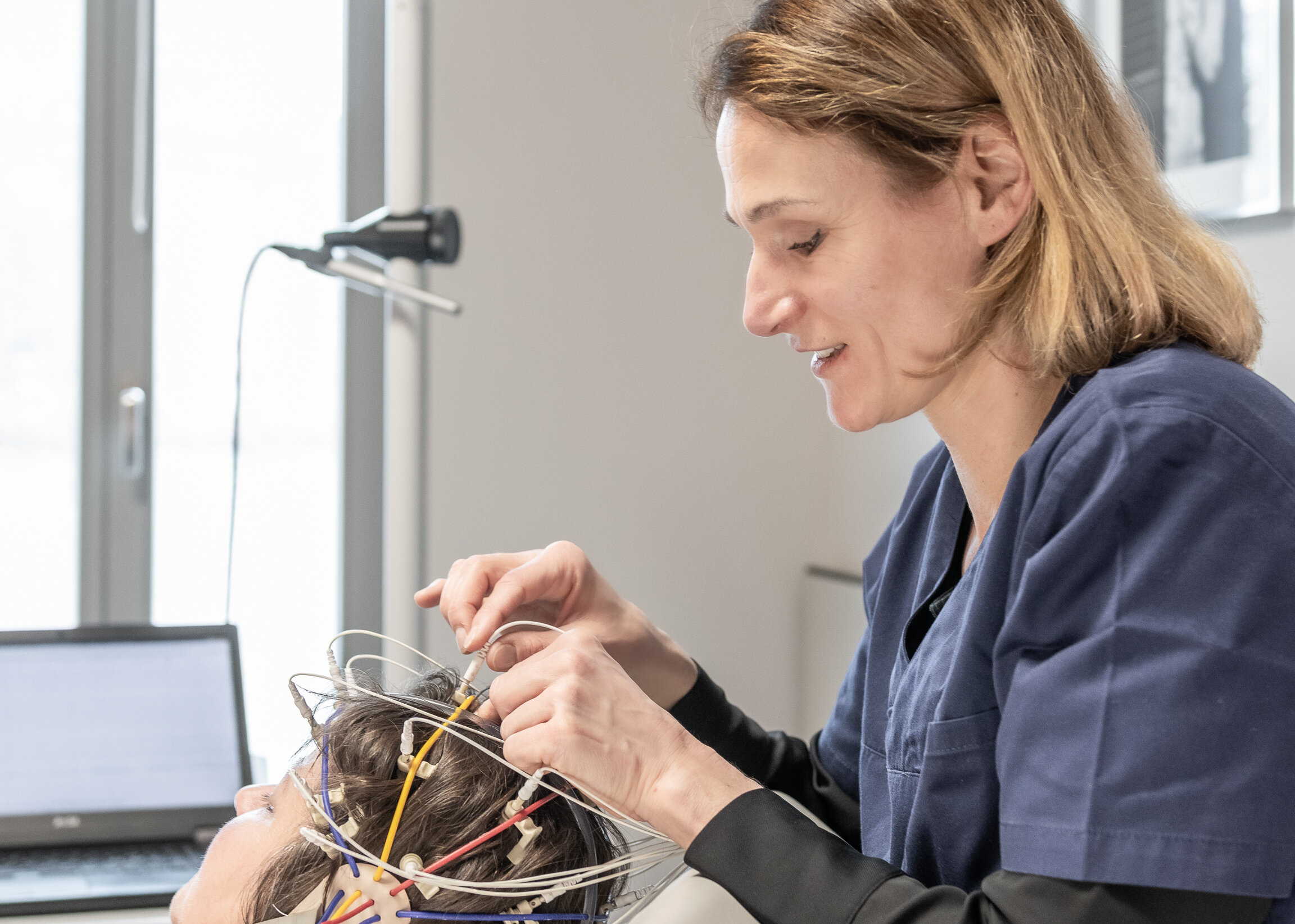 Eine Mitarbeiterin des Neurozentrums Aarau befestigt EEG-Elektroden am Kopf einer Patientin.