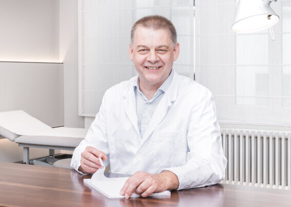 Der Neurologe, Dr. Arto Nirkko sitzt an seinem Schreibtisch und liest ein Dokument.