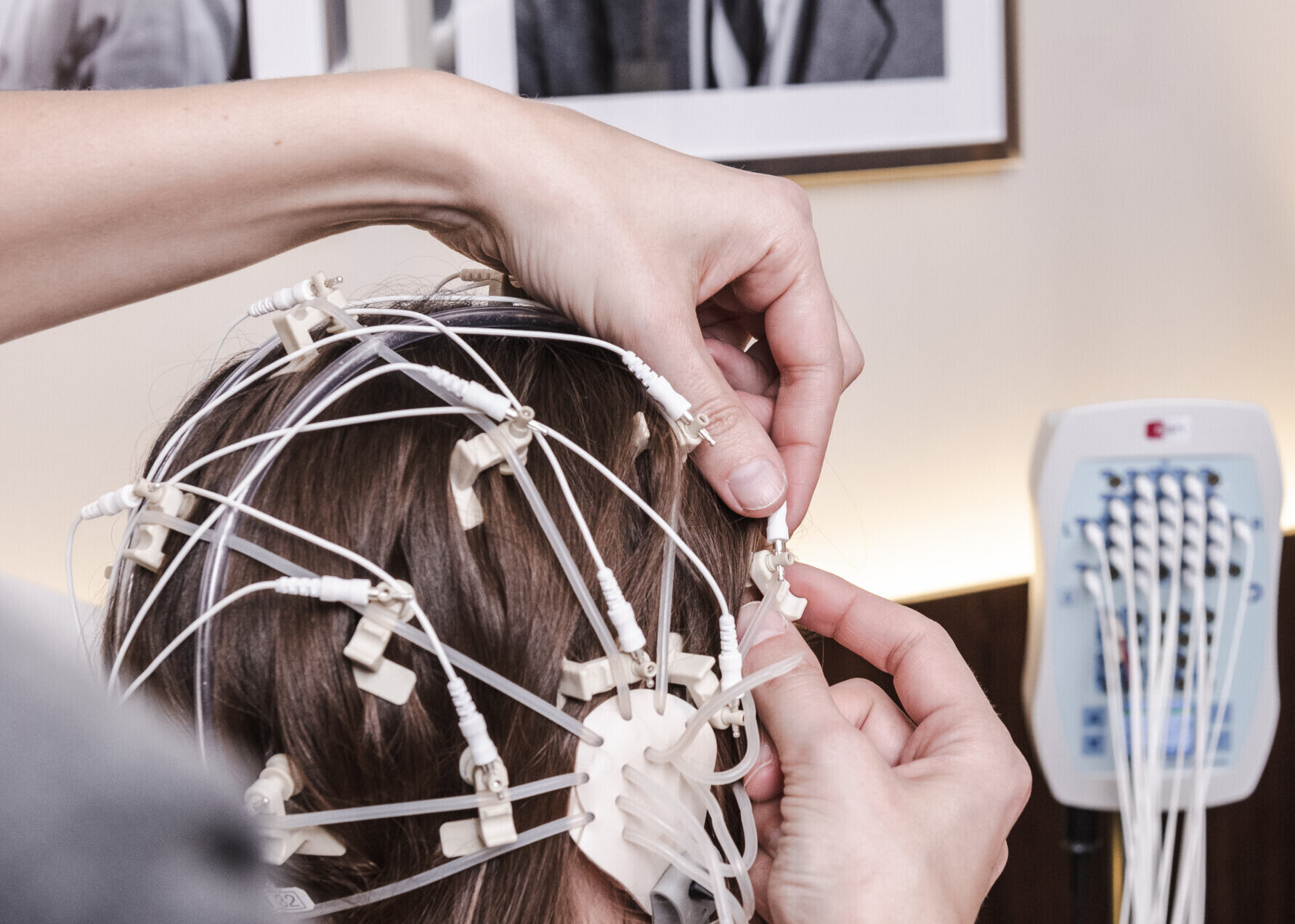 Eine Mitarbeiterin des Neurozentrums Bellevue befestigt EEG-Elektroden am Kopf einer Patientin.