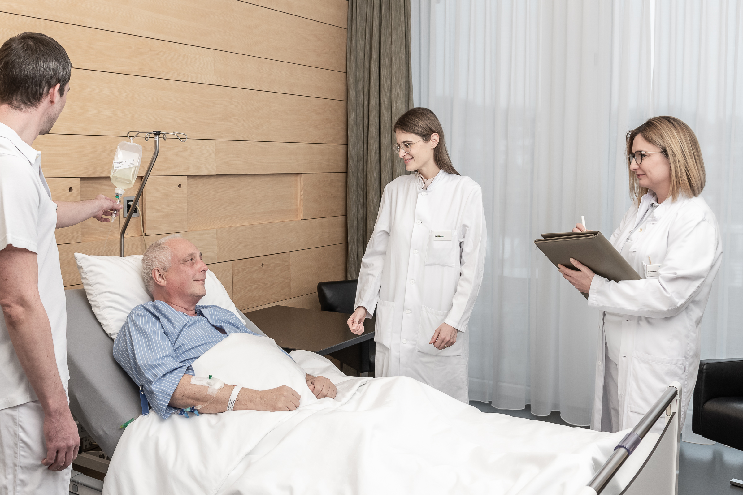 Mehrere Ärzte betreuen einen Patienten, der im Bett liegt.
