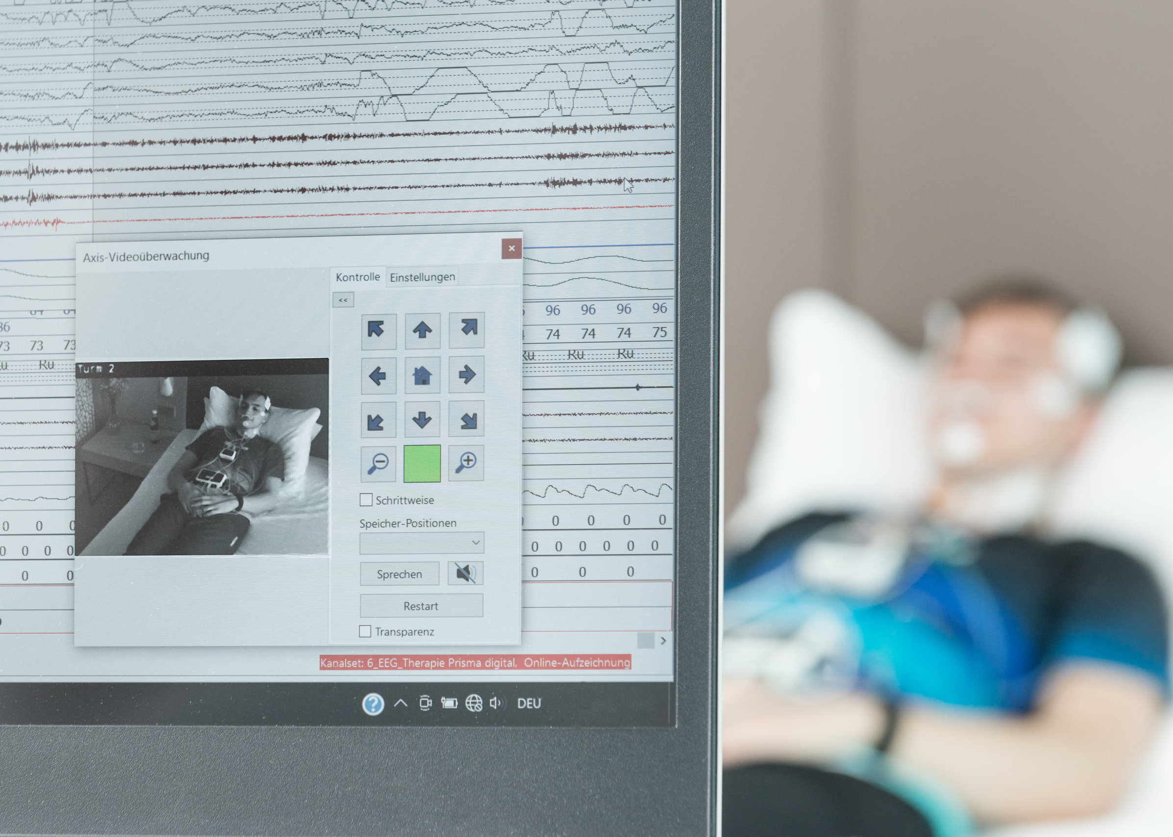 Auf einem Bildschirm sind die Ergebnisse einer Schlafuntersuchung zu sehen. Patient im Hintergrund.